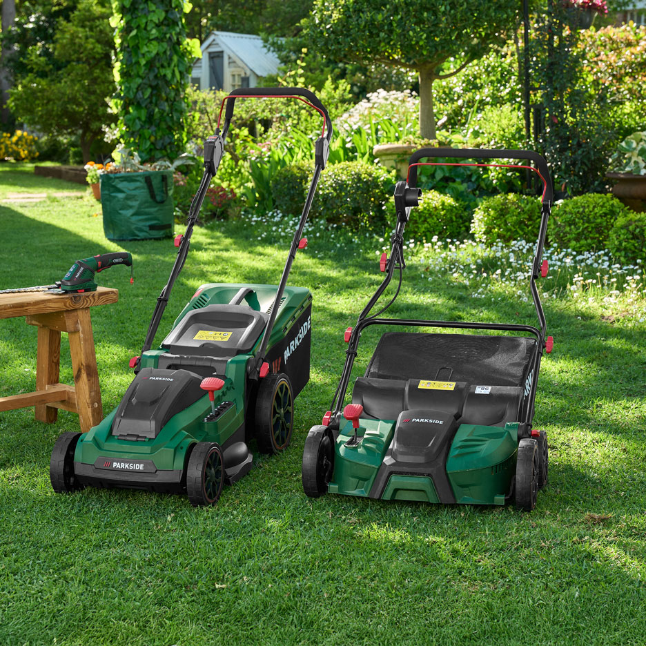 Two green lawnmowers and a hedge trimmer on a wooden bench in a sunny garden.