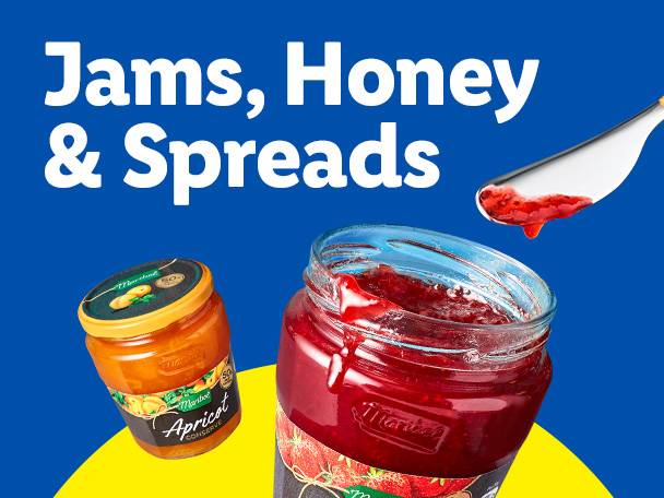Jars of apricot and strawberry jam with a spoon of strawberry jam.