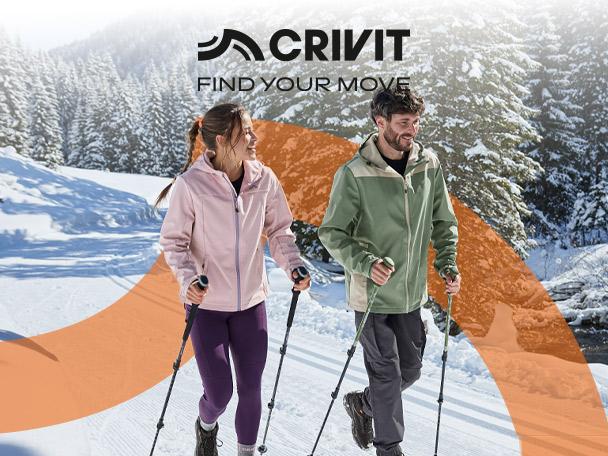 A man and a woman hiking in the snow wearing outdoor jackets and using trekking poles.