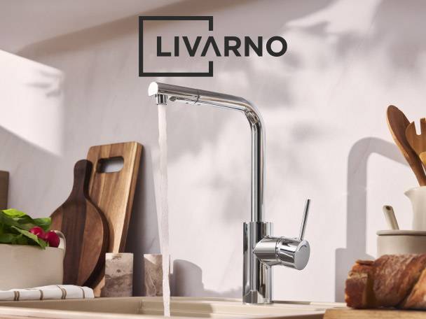 Chrome kitchen tap with running water, cutting boards, and fresh produce.