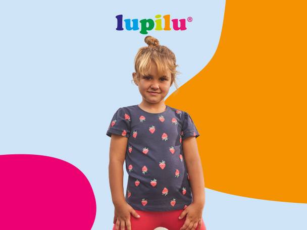 Young girl in a dark blue t-shirt with strawberry print and red pants.