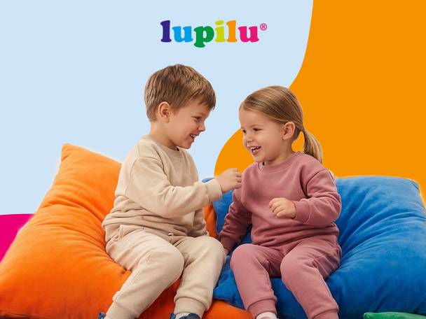 Two happy children in comfortable loungewear sitting on colorful bean bags.