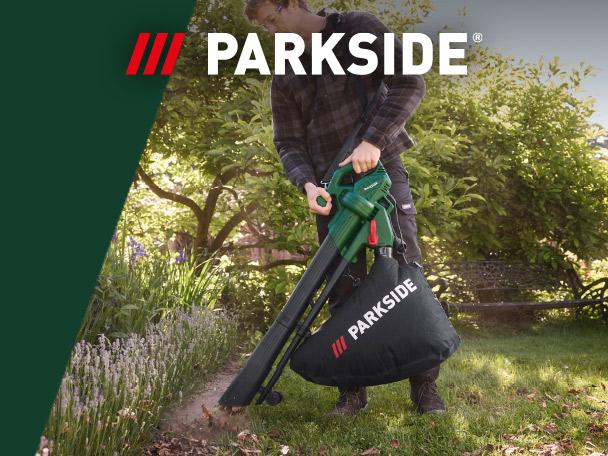 A man using a garden leaf blower and vacuum to clear leaves from a lawn.