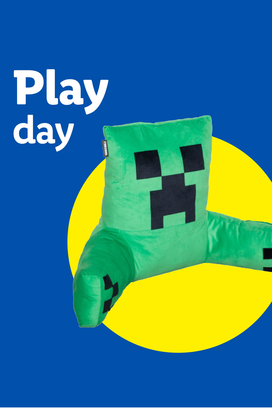 Green character pillow with black pixelated features on a blue and yellow background with text 'Play day'.