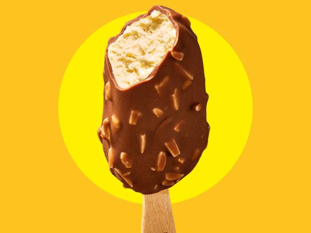 Chocolate-covered ice cream bar with nuts and a bite taken out, on a yellow background.